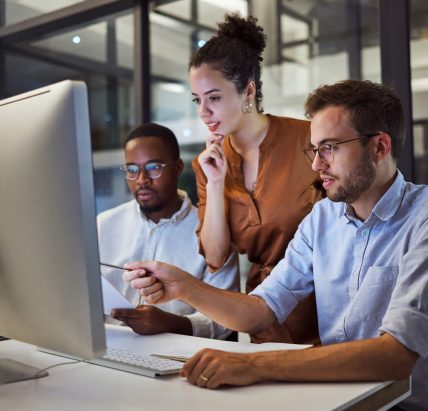 Team, office and computer in night workshop for planning, strategy or goal for business in overtime. Collaboration, teamwork and meeting at desk for creative vision, innovation or idea late at work.